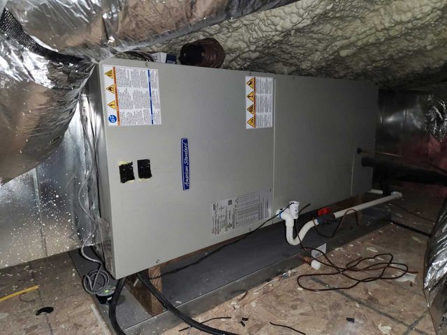 Indoor HVAC air handler installed in an attic with insulated duct connections.
