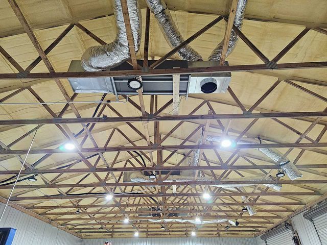 Commercial overhead ventilation and ductwork installed beneath open roof framing.