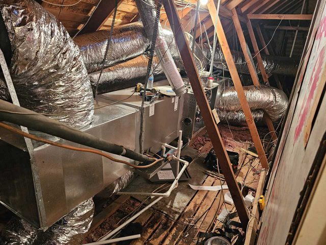 HVAC equipment and insulated ductwork routed through attic framing.