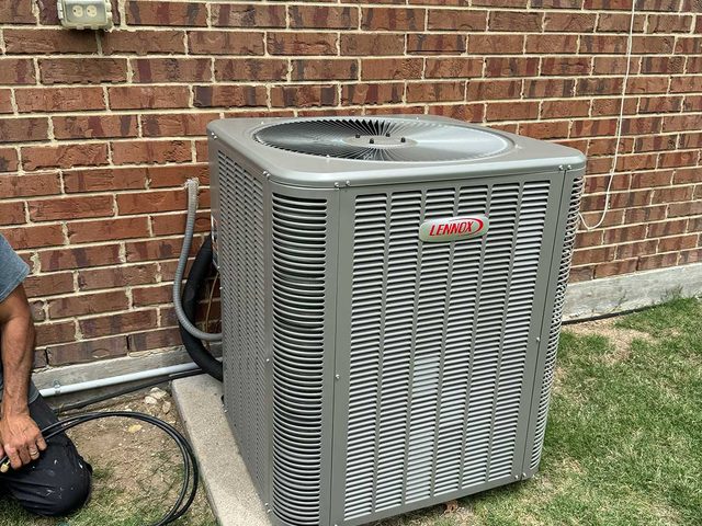 Residential outdoor air-conditioning condenser installed beside a brick home.