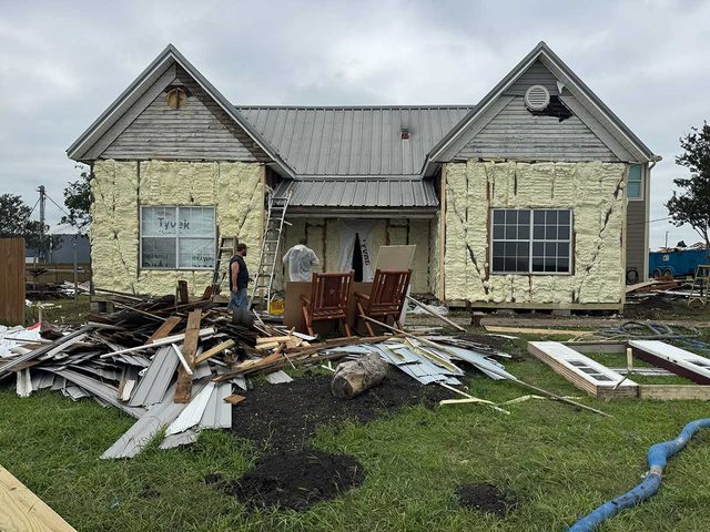 New-construction home receiving spray foam insulation before exterior completion.
