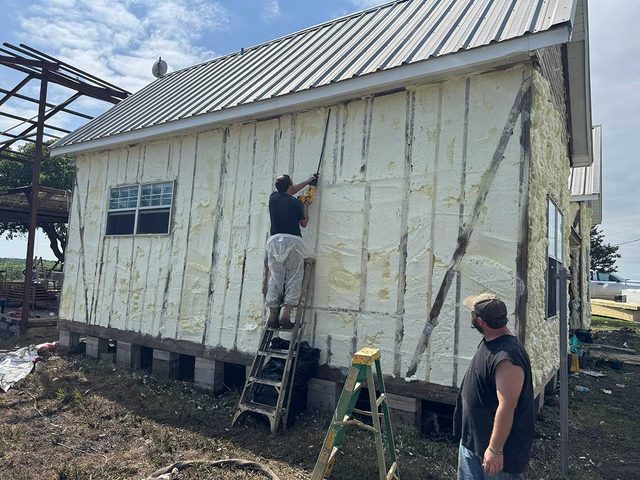 Technicians applying spray foam insulation to a new-construction exterior wall.