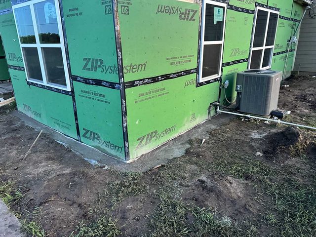 Wrapped exterior walls and HVAC equipment prepared during a new-construction project.