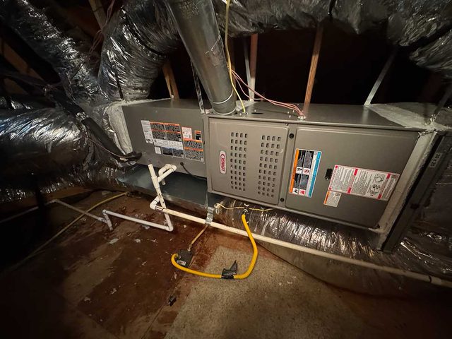 Residential attic HVAC equipment connected to insulated ductwork.