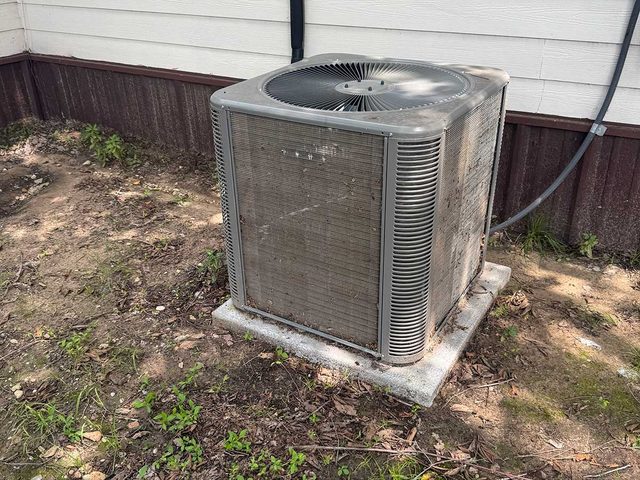 Residential air-conditioning condenser installed beside exterior siding.